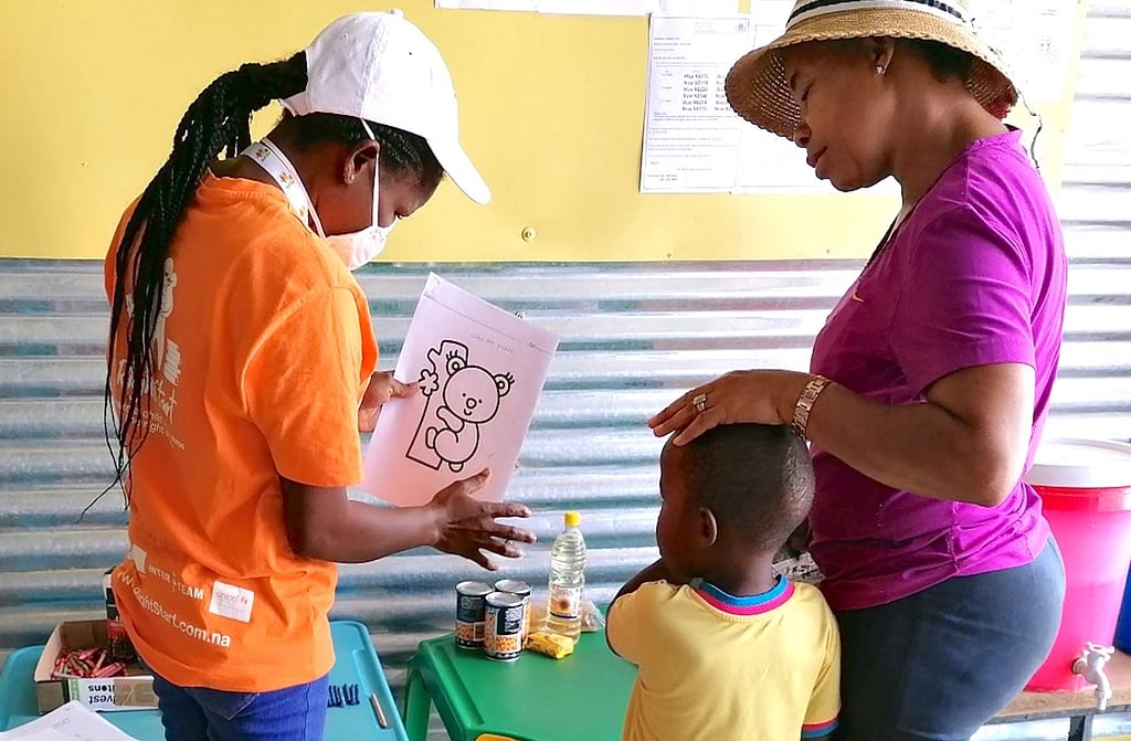 A teacher shows a picture to a child and his mother.