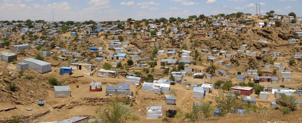 Many shacks scattered across a sandy valley.