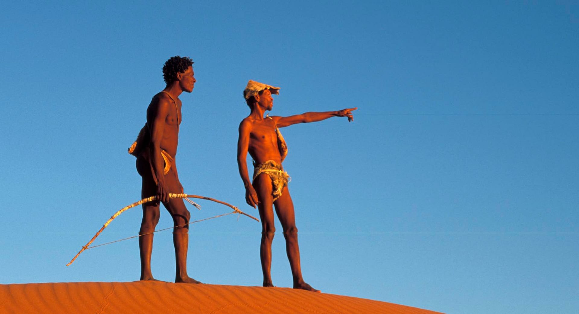 Two San hunters standing on a dune.