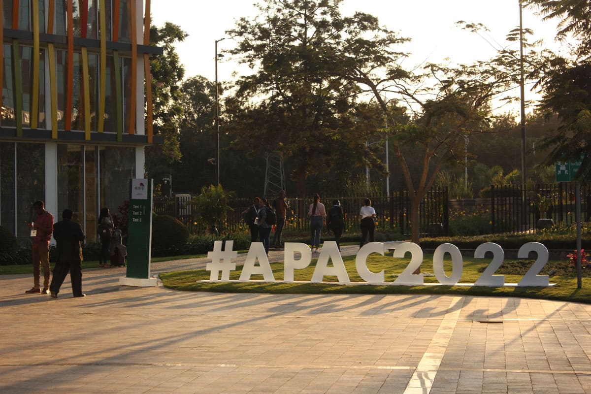 A sign on the ground outside a conference centre reads #apac2022.