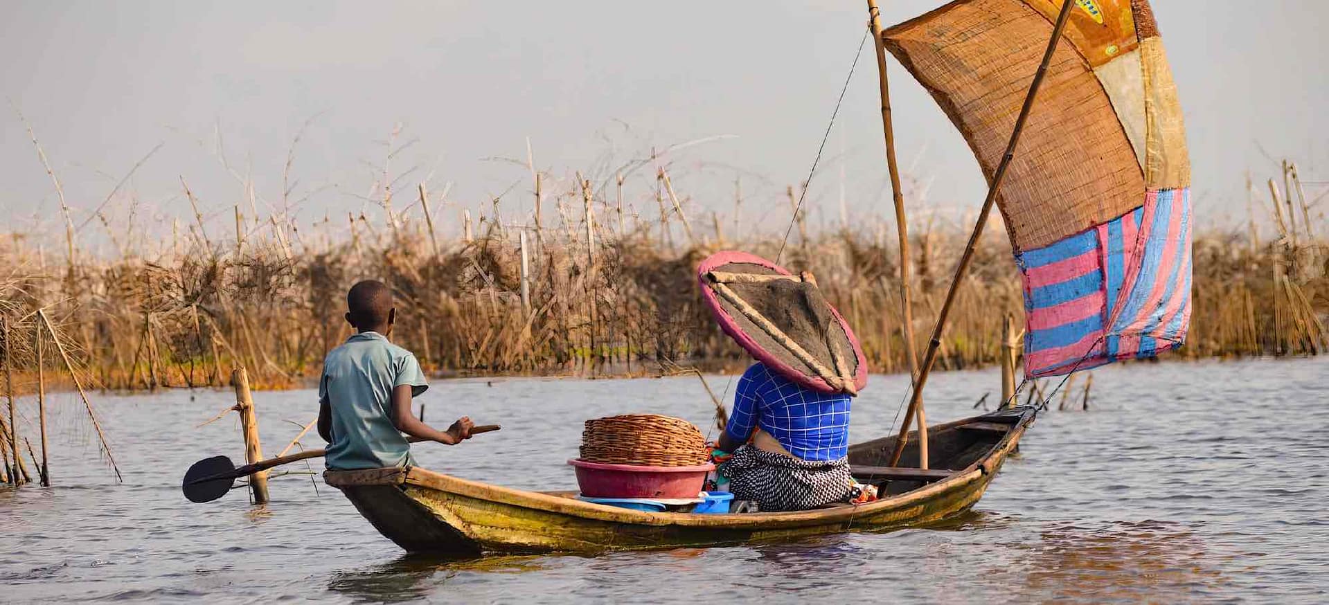A woman and child in a wooden boat in a river channel.